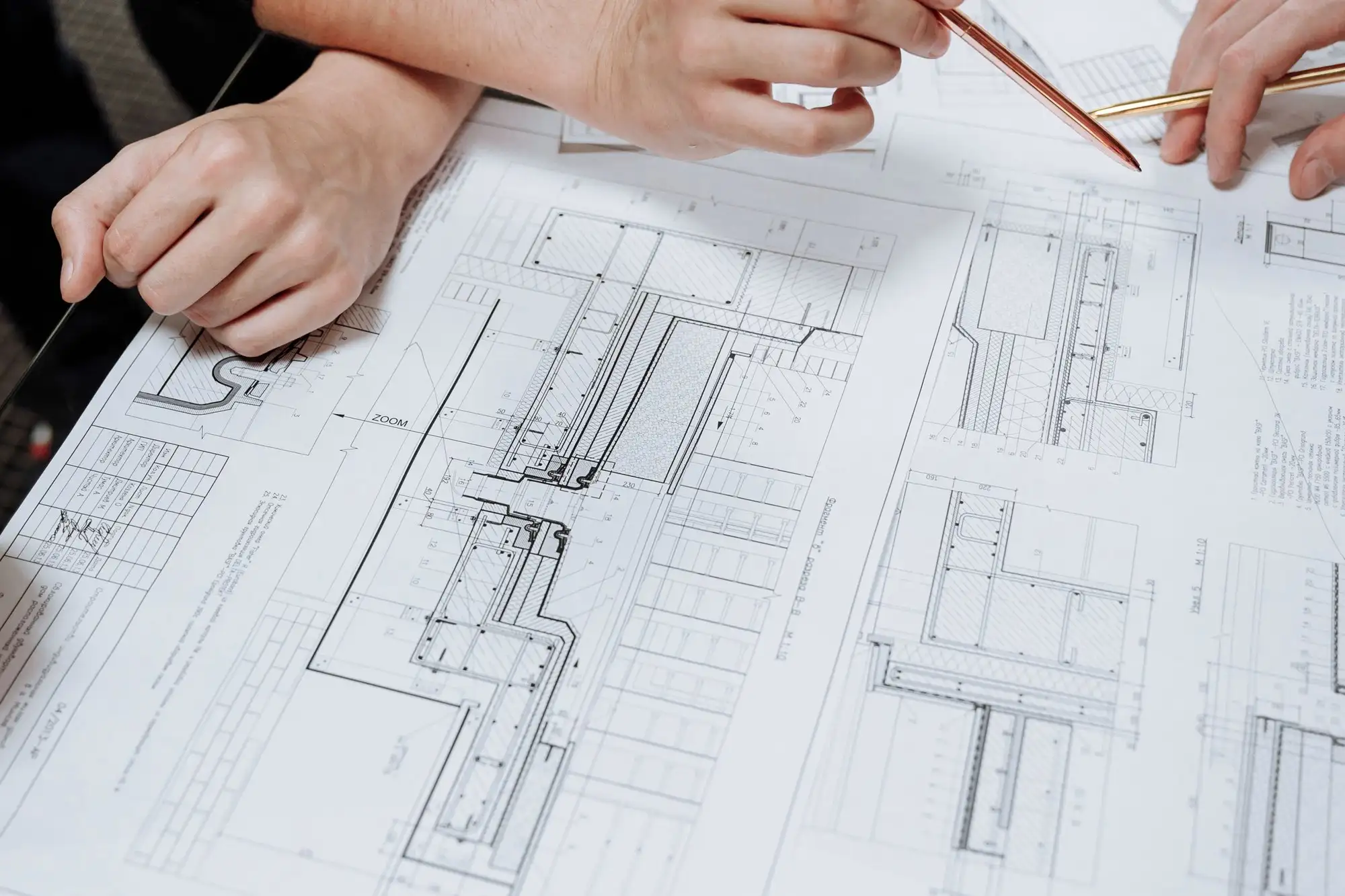 Mãos com lápis sobre plantas técnicas de arquitetura.